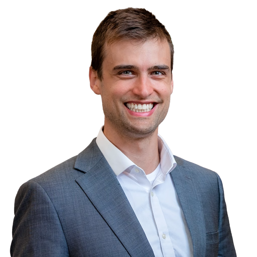 Photo of a white man with short brown hair, brown eyes, and he is wearing a gray suit jacket and white button down shirt